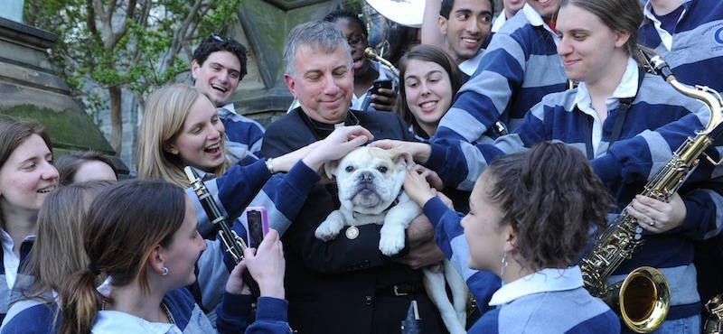 Father Steck holds Jack the Bulldog, surrounded by smiling members of the Georgetown Marching Band